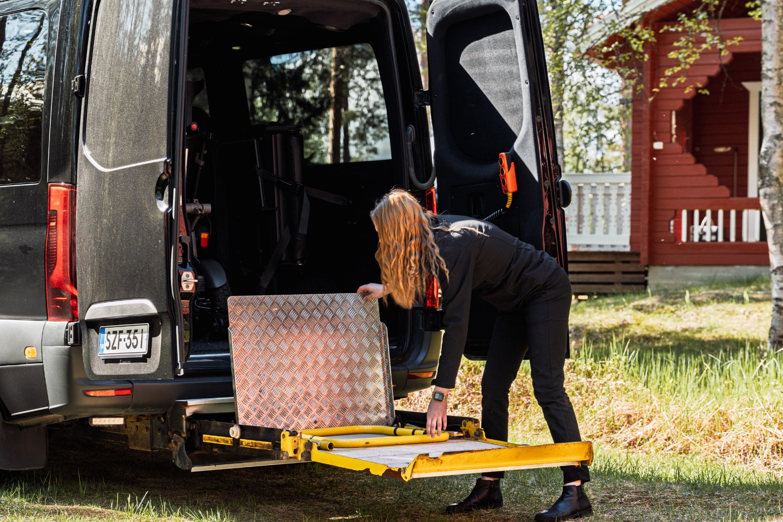 A Vulpes Aurora guide setting up the wheelchair lift at the back of the van.