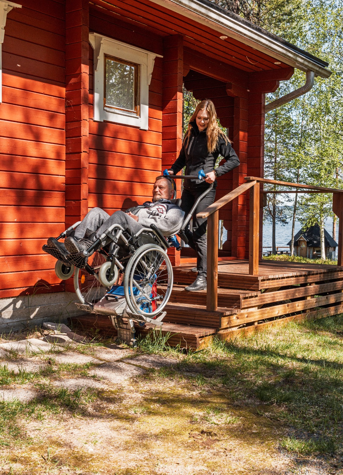 A Vulpes Aurora guide assisting a wheelchair user with a mobility lift in Lapland.